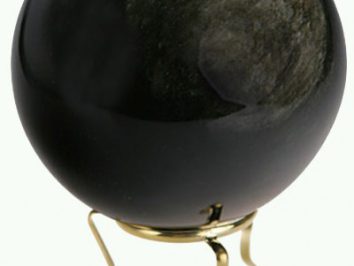 Czarna kula na złotym stojaku, używana do wróżenia lub dekoracji.