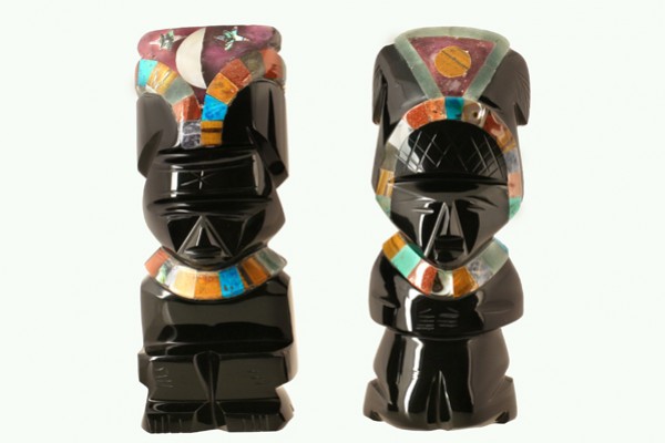 Dwie czarne figurki z kolorowymi ozdobami przedstawiające postacie w tradycyjnych nakryciach głowy.