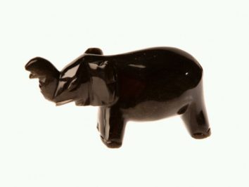 Czarna figurka słonia z podniesioną trąbą na jasnym tle.