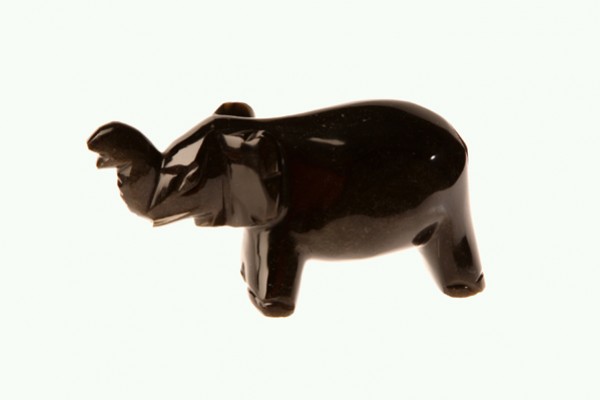 Czarna figurka słonia z podniesioną trąbą na jasnym tle.