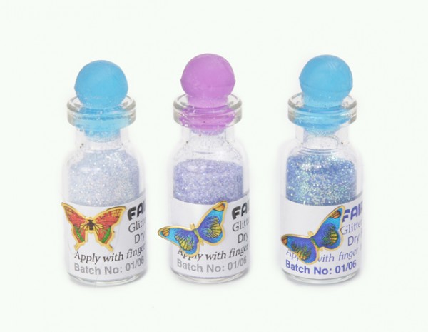 Trzy buteleczki z kolorowym brokatem do makijażu, każda ozdobiona naklejką z motylem.