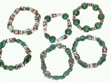 Sześć zielonych bransoletek złożonych z koralików o różnych wzorach ułożonych w okręgi.
