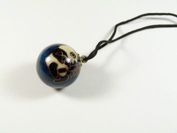 Wisiorek z ciemną kulą ozdobioną wzorem zwierzęcia, zawieszony na czarnym sznurku.
