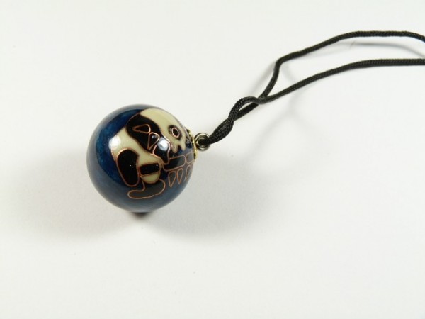 Wisiorek z ciemną kulą ozdobioną wzorem zwierzęcia, zawieszony na czarnym sznurku.