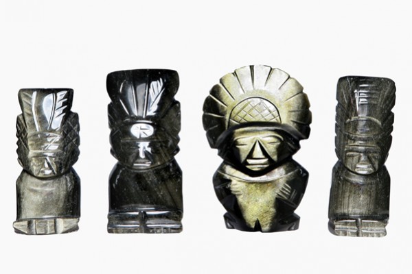 Cztery rzeźby przedstawiające postacie w pióropuszach ustawione obok siebie na białym tle.