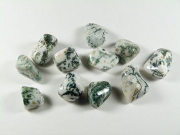 Polerowane kamienie zielonego agatu mszystego ułożone na białym tle.