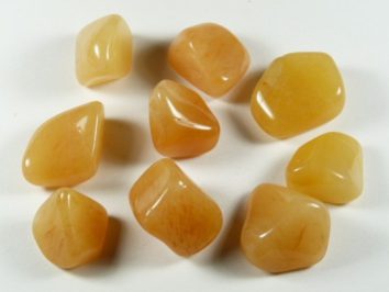 Dziewięć polerowanych kamieni pomarańczowych leży na białym tle.