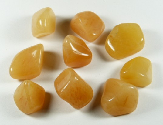 Dziewięć polerowanych kamieni pomarańczowych leży na białym tle.