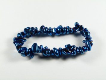 Bransoletka z niebieskich, nieregularnych kamieni na białym tle.