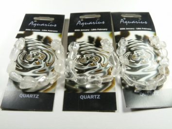 Trzy bransoletki z kwarcu na kartonikach z napisem "Aquarius" i datami znaku zodiaku.