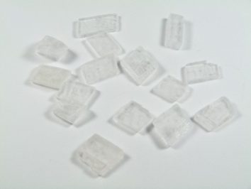 Spar islandzki - kamień naturalny, surowy, nieszlifowany. Kilka białych kryształków na białym tle.