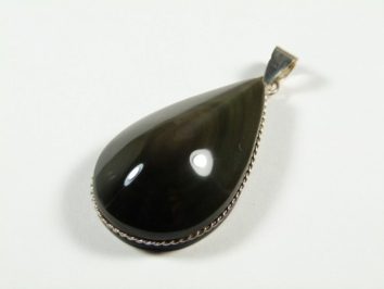 Czarny, łezkowaty wisior z połyskującym kamieniem w srebrnej oprawie na białym tle.