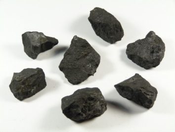 Siedem kawałków czarnego węgla kamiennego na białym tle.
