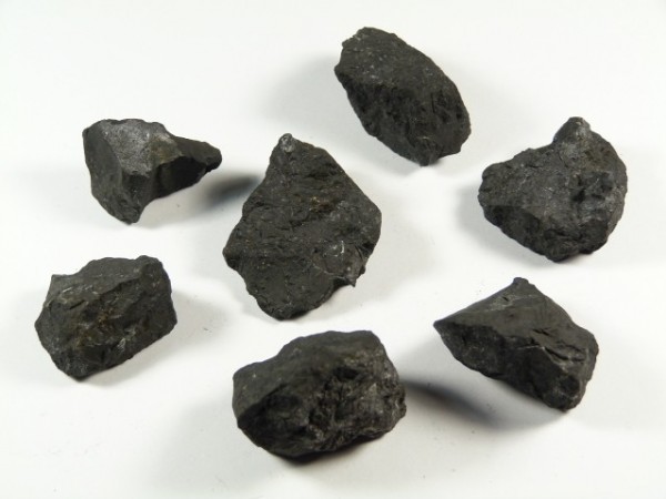 Siedem kawałków czarnego węgla kamiennego na białym tle.