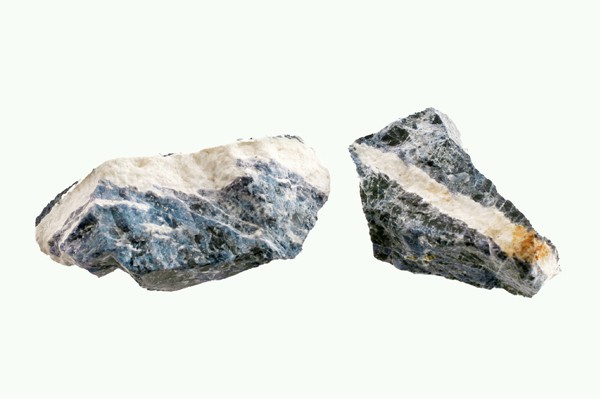Dwa nieoszlifowane kawałki minerału o niebiesko-białym zabarwieniu na jasnym tle.