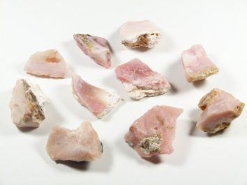 Dziewięć surowych różowych kamieni ułożonych na białym tle.