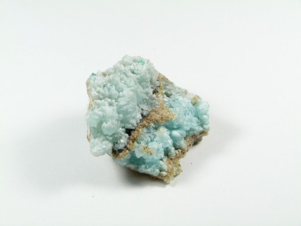 Hemimorfit - kamień naturalny, surowy, nieszlifowany. Jasnoniebieski minerał z kryształkami na białym tle.