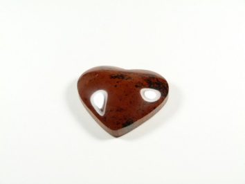 Brązowy kamień w kształcie serca z dwoma wycięciami leży na białym tle.