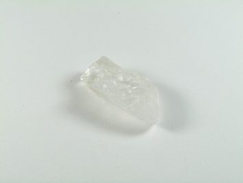 Przezroczysty kryształ leży na białym tle.