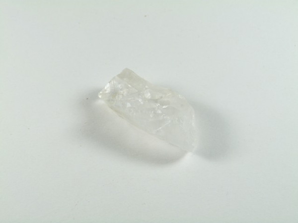 Przezroczysty kryształ leży na białym tle.