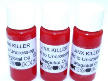 Trzy buteleczki z czerwonym olejkiem magii opisane jako "Jinx Killer Magickal Oil".
