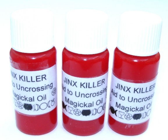 Trzy buteleczki z czerwonym olejkiem magii opisane jako "Jinx Killer Magickal Oil".