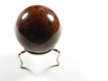 Brązowa kula z czarno-czerwonymi plamami na metalowym stojaku, na białym tle.