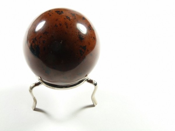 Brązowa kula z czarno-czerwonymi plamami na metalowym stojaku, na białym tle.