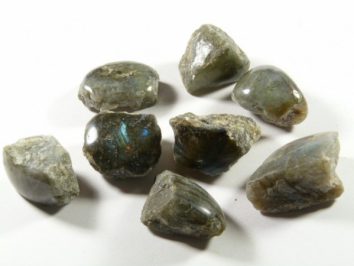 Labradoryt - kamień naturalny, surowy, nieszlifowany. Siedem nieoszlifowanych kamieni labradorytu na białym tle.