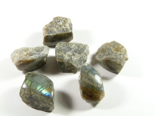 Sześć surowych kamieni labradorytu na białym tle.