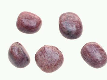 Mika czerwona - kamień gładzony, polerowany, szlifowany i bębnowany w formie otoczaka. Pięć gładkich, fioletowych kamieni ułożonych na jasnym tle.