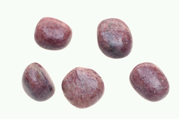 Mika czerwona - kamień gładzony, polerowany, szlifowany i bębnowany w formie otoczaka. Pięć gładkich, fioletowych kamieni ułożonych na jasnym tle.
