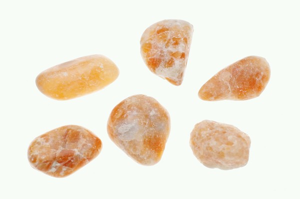 Kalcyt orchid/ kalcyt orchidea - kamień gładzony, polerowany, szlifowany i bębnowany w formie otoczaka. Sześć gładkich, pomarańczowych kamieni leży na białym tle.