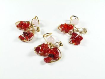 Trzy pary kolczyków z czerwonymi kamieniami i złotym drutem na białym tle.