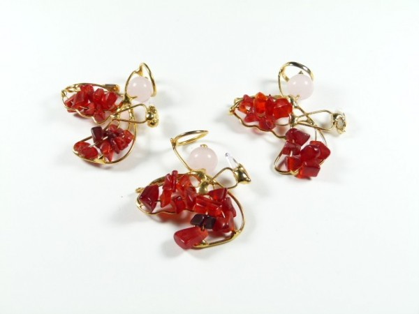 Trzy pary kolczyków z czerwonymi kamieniami i złotym drutem na białym tle.
