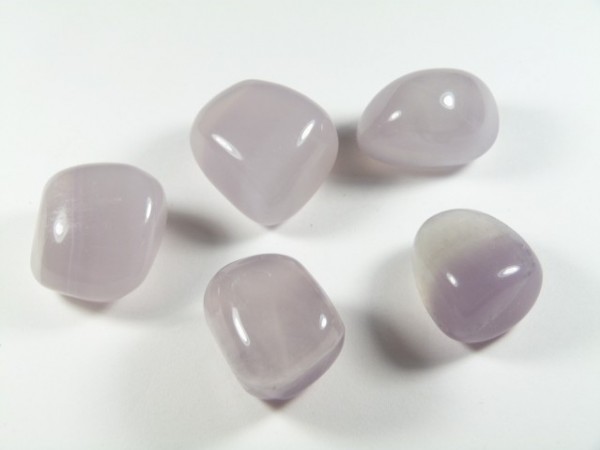 Pięć gładkich, jasno-fioletowych kamieni leży na białym tle.