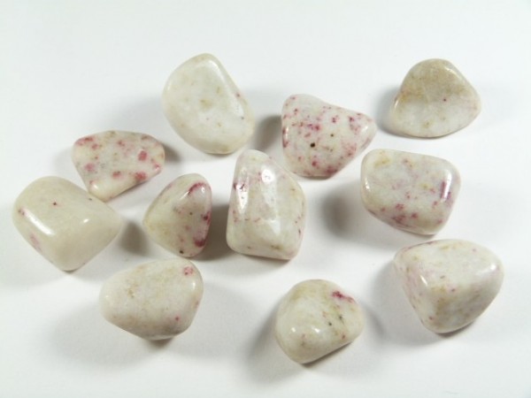 Gładkie białe kamienie z drobnymi różowymi plamkami, ułożone na białym tle.
