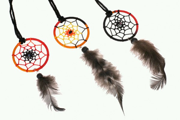 Trzy kolorowe łapacze snów z piórami wiszą na czarnych sznurkach.