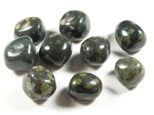 Lakelandyt - kamień gładzony, polerowany, szlifowany i bębnowany w formie otoczaka. Dziewięć połyskujących, zielonych kamieni z jasnymi plamkami na białym tle.