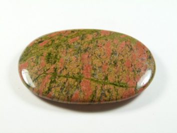 Unakit - kamień gładzony, polerowany, szlifowany. Polerowany, owalny kamień unakitu w kolorach zielonym i różowym na białym tle.