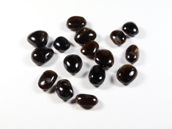 Kilka wypolerowanych, ciemnych kamieni leży na białym tle.