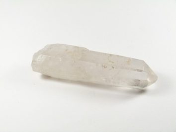 Przezroczysty kryształ kwarcu leżący na białym tle.