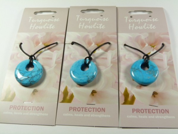 Trzy naszyjniki z turkusem na czarnych sznurkach, każdy na kartoniku z napisem "Protection".