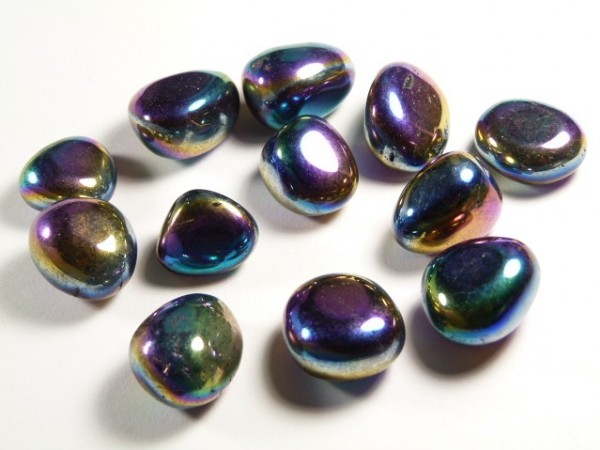 Kolorowe, opalizujące kamienie ułożone na białym tle.