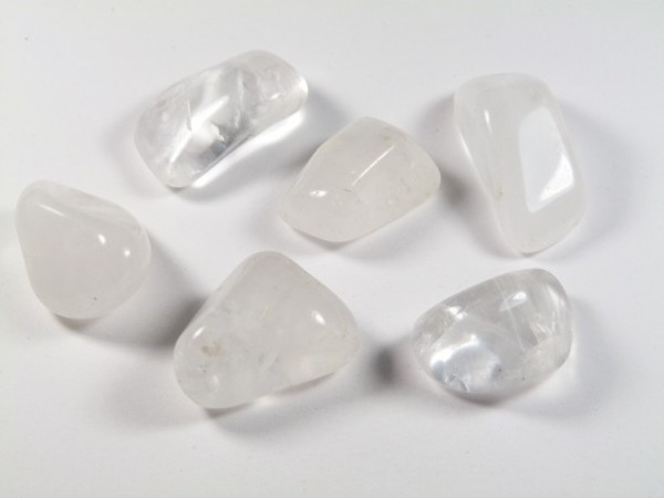 Sześć gładkich, białych kamieni leży na białym tle.