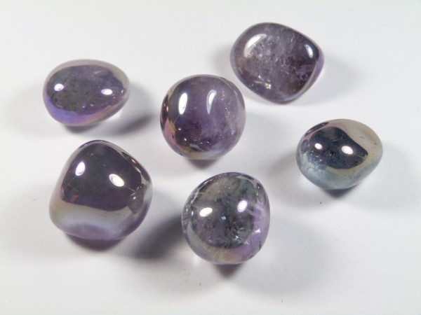 Sześć polerowanych fioletowych kamieni leży na białym tle.
