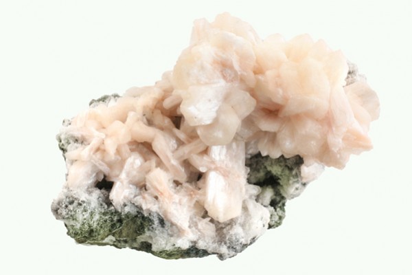 Stilbit - kamień naturalny, surowy, nieszlifowany. Różowy kryształ stilbit na zielono-białej skale, widok z bliska.