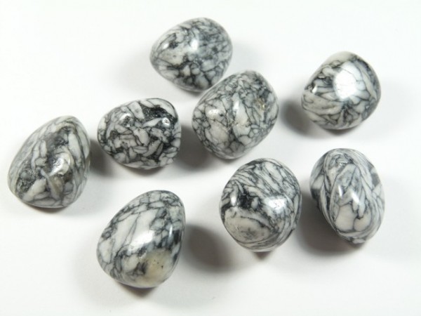 Osiem polerowanych kamieni marmurowych o szaro-czarnych żyłkach na białym tle.