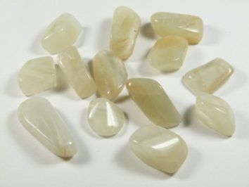 Kilka jasnych, gładkich kamieni ułożonych na białym tle.