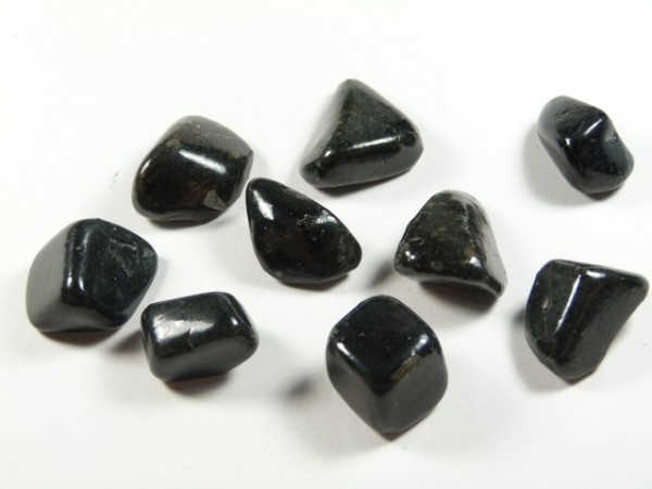 Osiem czarnych, wypolerowanych kamieni leży na białym tle.